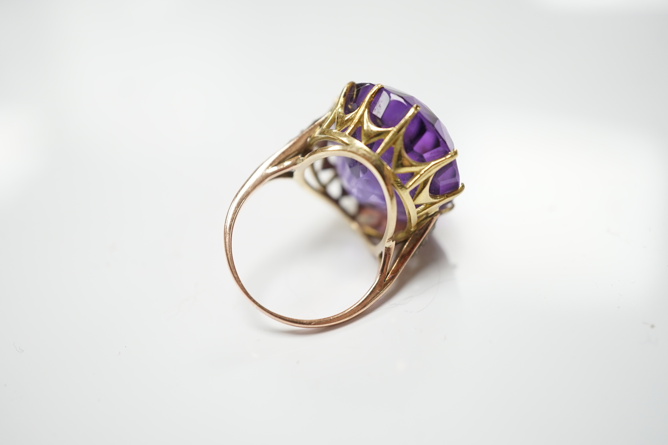 A yellow metal and oval cut amethyst set dress ring, with diamond chip set shoulders, size O, gross weight 10.6 grams.